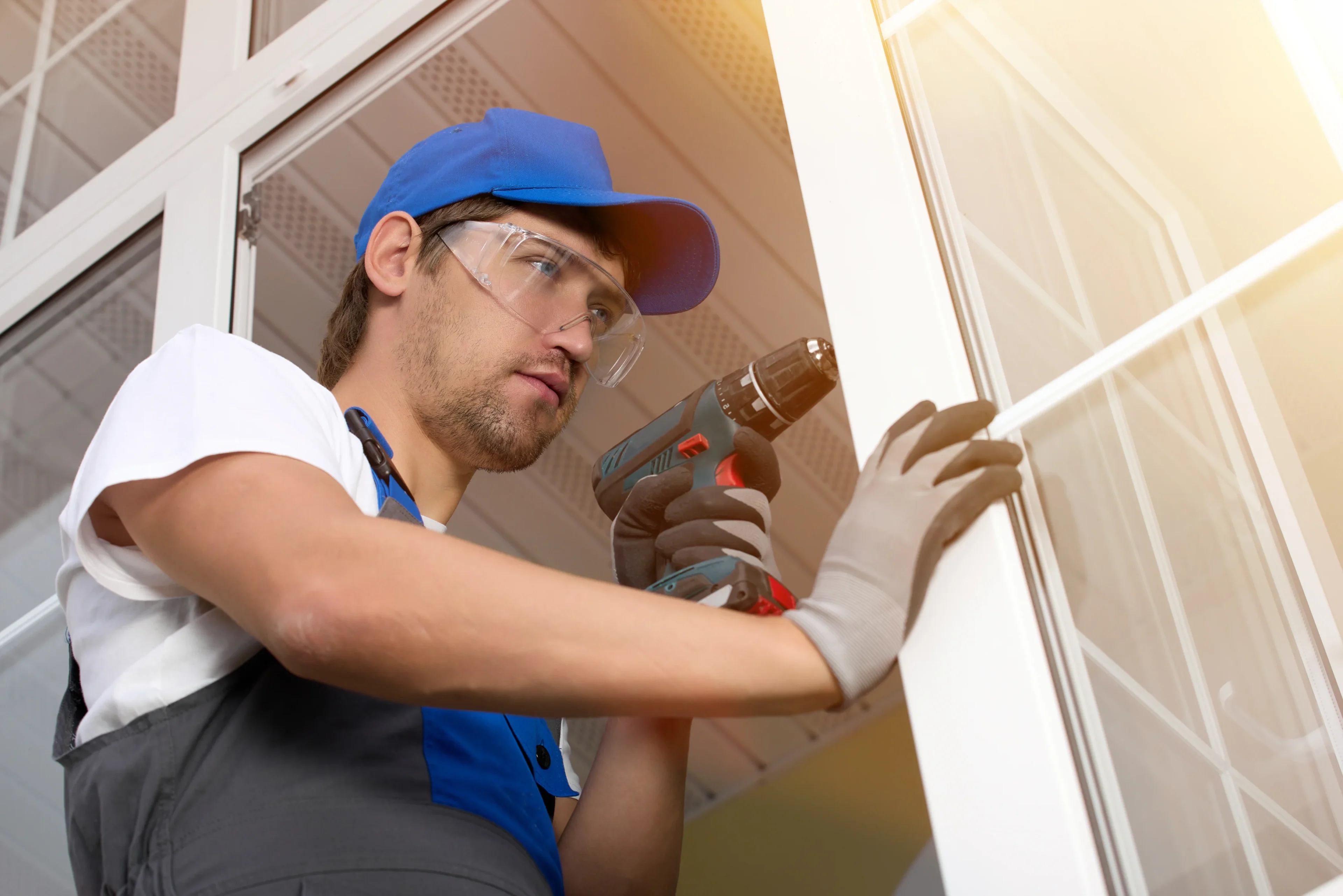 Here's an alt tag for the image: Worker installing window with drill.